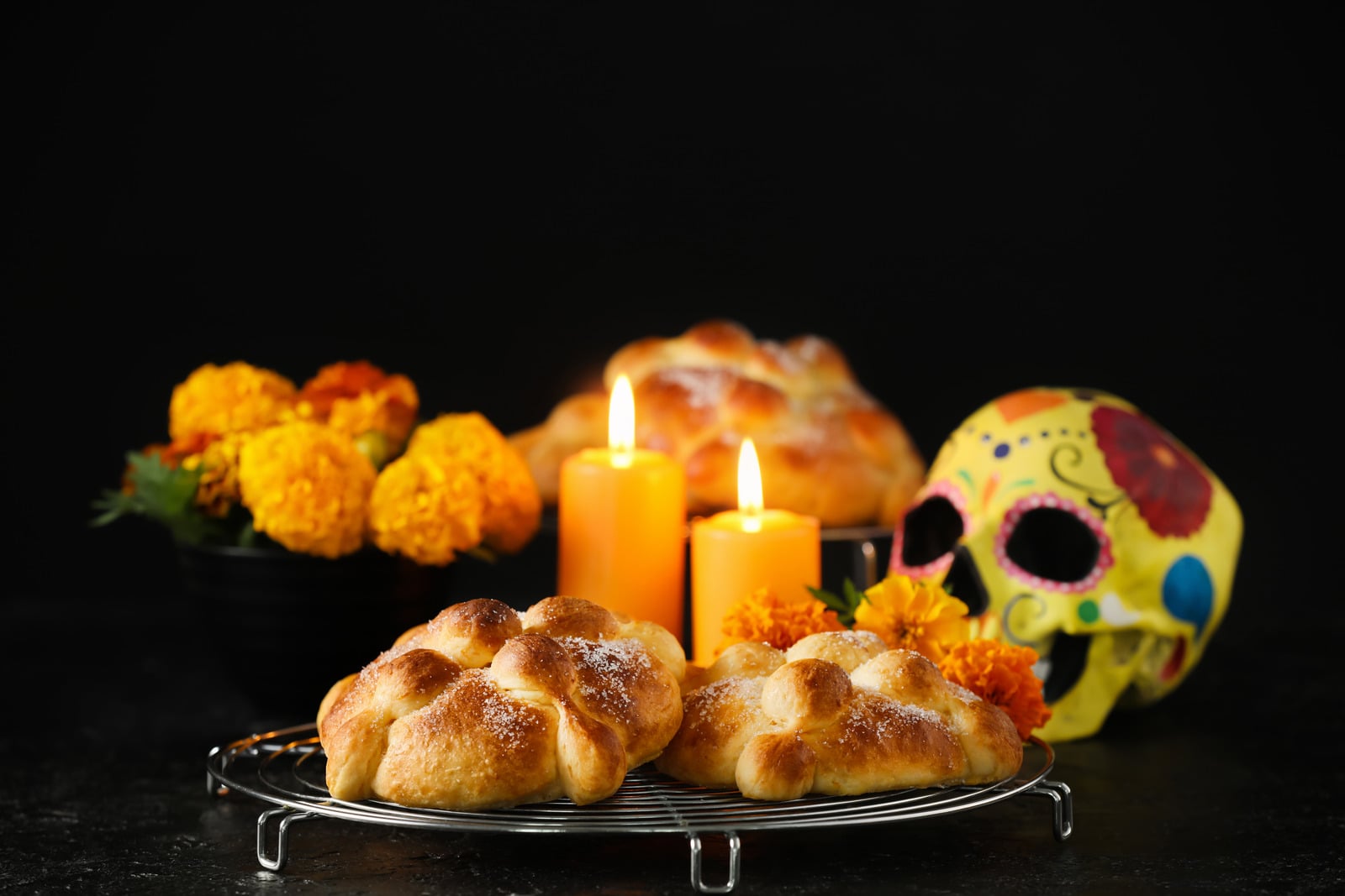 Official gala page illustration with pan de muerto, marigolds, candles and a decorated skull; not a photograph of the upcoming event.