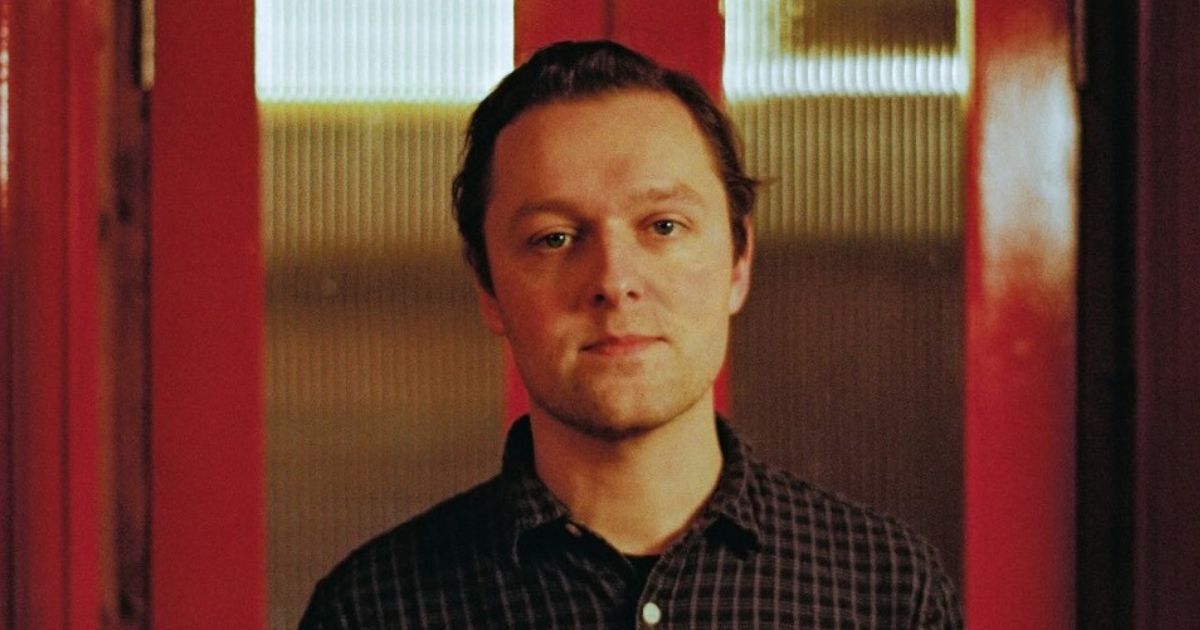 Official venue portrait of Joshua Burnside against red and cream panels